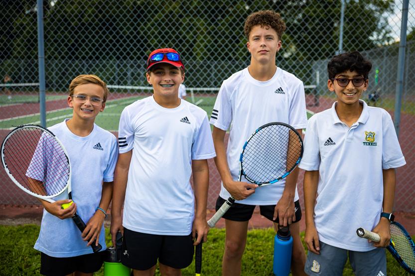 Four tennis players smile